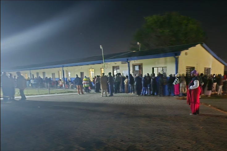 Menschen in einer Schlange vor einem nächtlichen Wahllokal