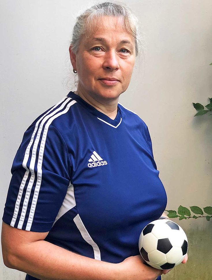 Friederike Pfaffinger im Fußballtrikot des Vereins, hält einen kleinen Fußball in der Hand und blickt in die Kamera.