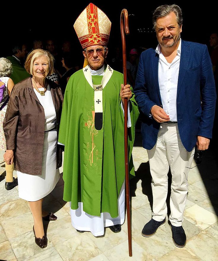 Ursula Männle steht links neben einem eindeutigen Erzbischof mit typischem Bischofshut und Kromstab. Mann in Blazer rechts daneben.
