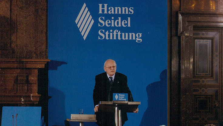 Mann an Rednerpult vor Logo der Hanns-Seidel-Stiftung