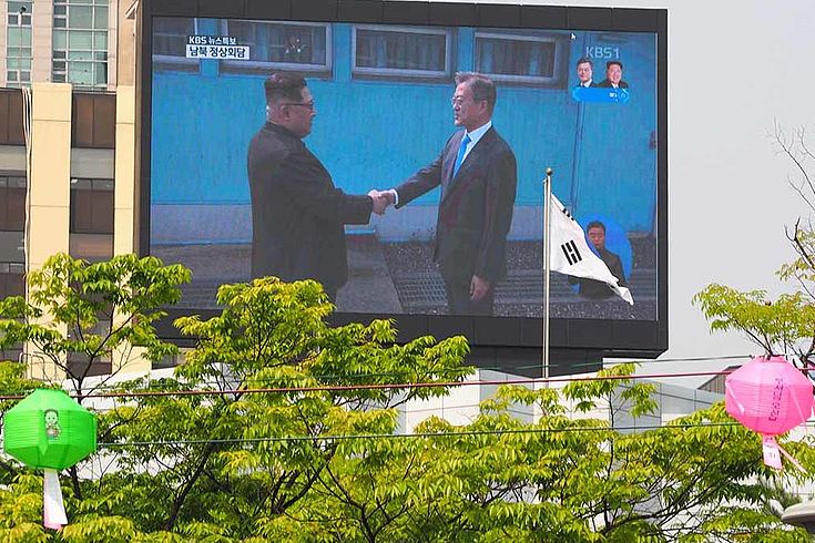 Kim Jong-Un und Moon Jae-In reichen sich an der innerkoreanischen Grenze die Hand.