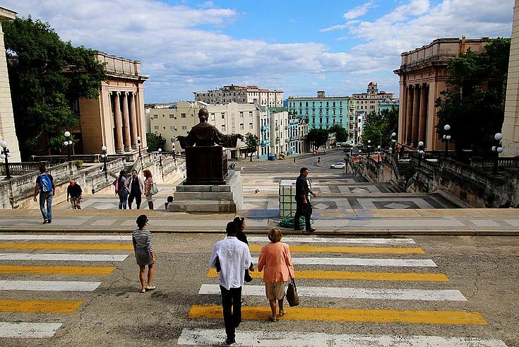 Weites Bullevard mit einer Messingstatue mittig. Rechts und links der Straße die altmodischen Häuser Havannas.