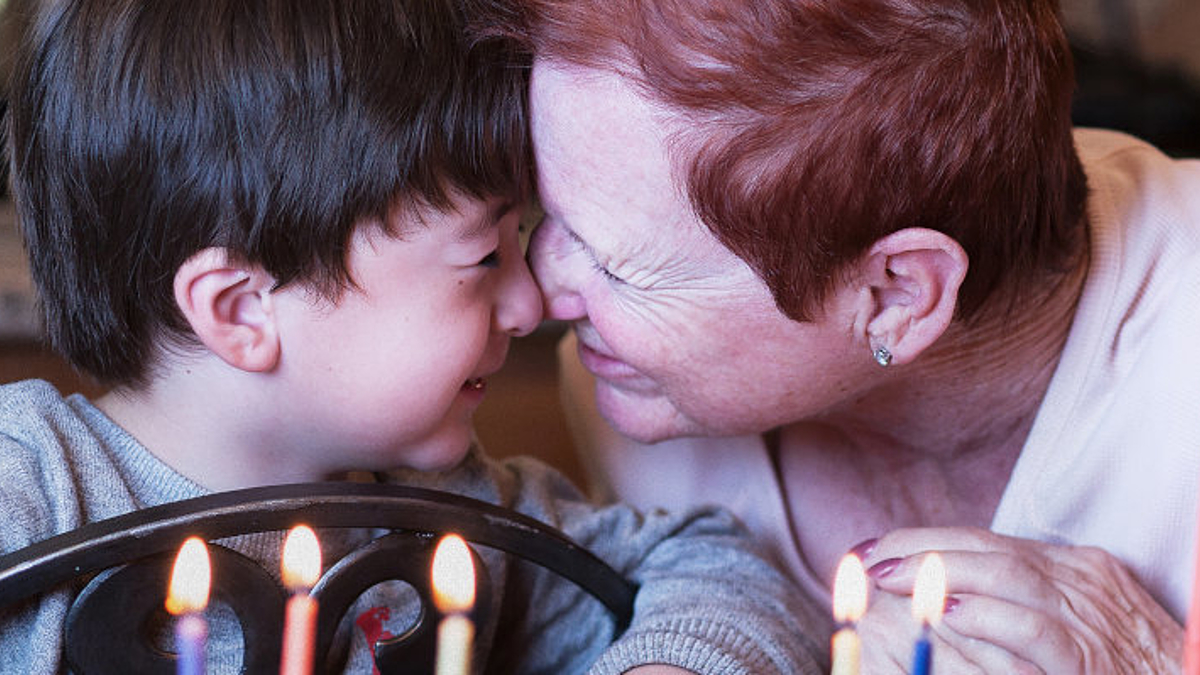 Junge und Großmutter feiern gemeinsam, auf dem Tisch stehen Kerzen