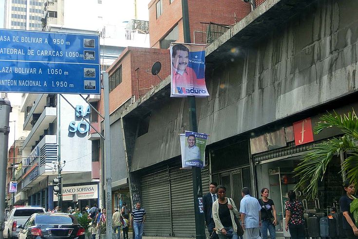 Straßenbild mit vielen Wahlplakaten und Passanten