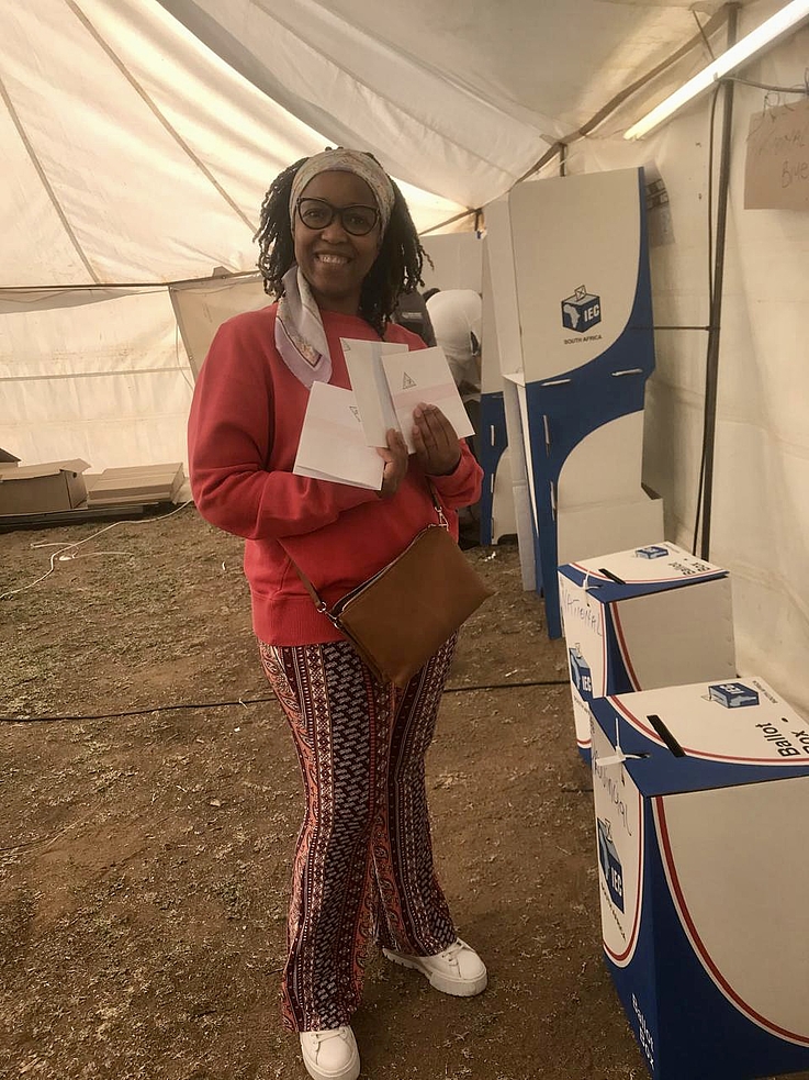 Frau Mokoena lächelnd vor der Wahlurne
