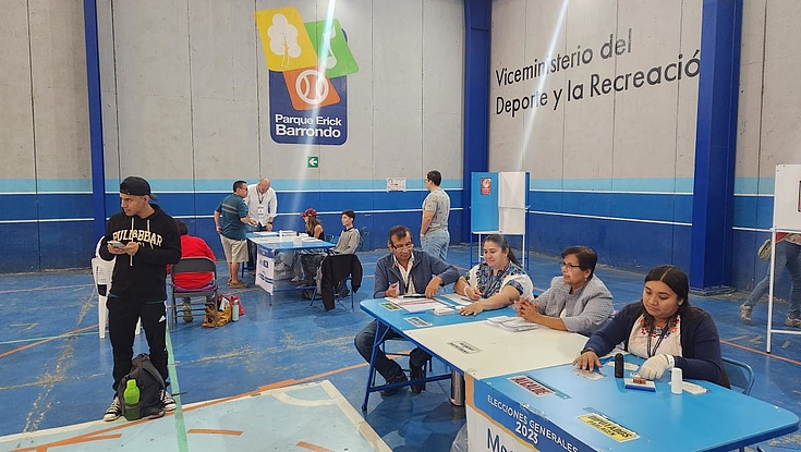 Menschen in einer Turnhalle, die zum Wahllokal umgestaltet wurde.