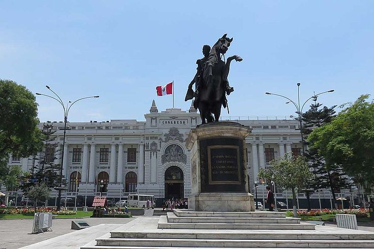 Das weiße Kongress-Gebäudes des peruanischen Parlamentes wird von Bäumen umrahmt. Davor steht ein Reiterdenkmal.
