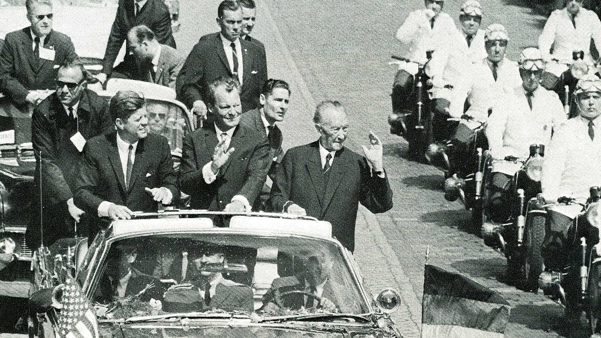John F. Kennedy, Präsident der USA (1961-1963); Konrad Adenauer, der erste Bundeskanzler (1949-1963) und Willy Brandt, vierter Bundeskanzler (1969-1974), reisen in der Präsidentenlimousine durch Berlin. Während des Besuchs von JFK in der Bundesrepublik Deutschland am 26. Juni 1963 jubelt ihnen die Menge zu.
