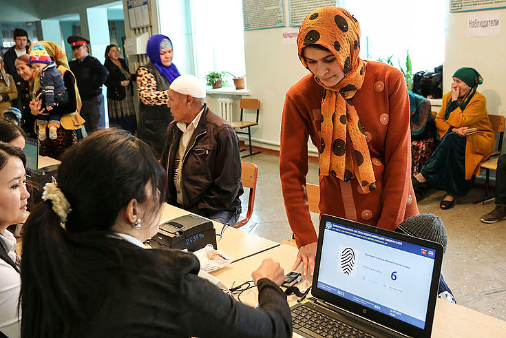 In einem Wahllokal wird eine Wählerin im traditionellen Gewand biometrisch erfasst