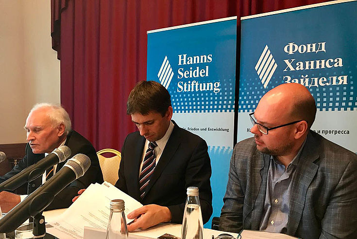 Drei Herren kramen in Unterlagen während einer Konferenz. In der Mitte unser Verbindungsstellenleiter für Moskau, Jan Dresel.