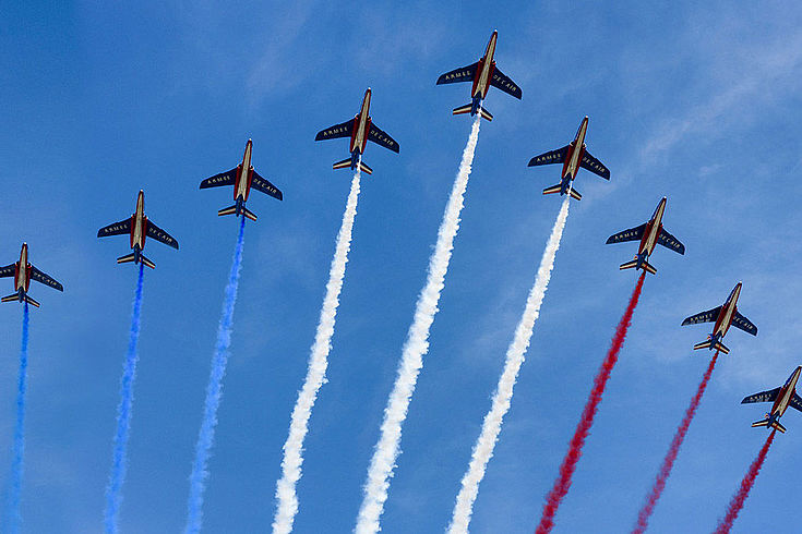 Kampfflugzeuge im Formationsflug versprühen blau, weiß, roten Rauch hinter sich, die Farben der Niederländischen Nationalflagge.